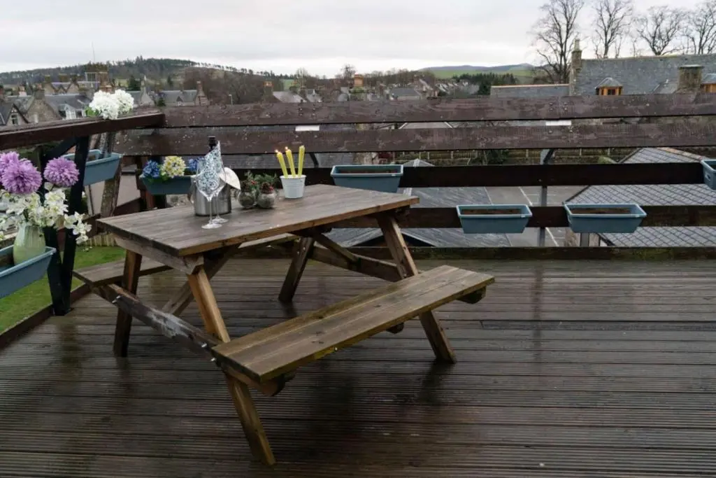 a wooden picnic table on a deck with a bench at Dunedin House in Huntly