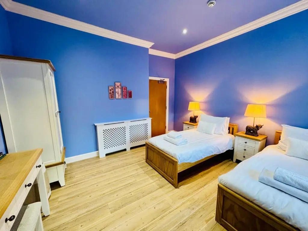 a bedroom with two beds and a blue wall at Entirely New Monastery Renovation on Loch Ness in Fort Augustus