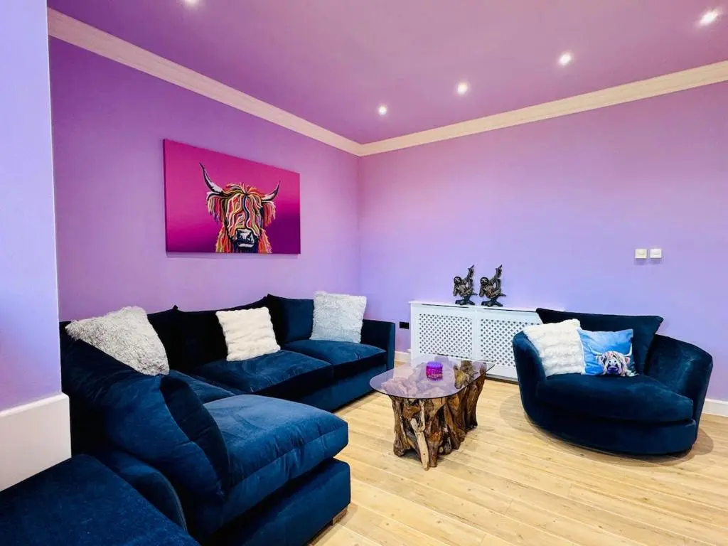 a living room with purple walls and blue couches and a table at Entirely New Monastery Renovation on Loch Ness in Fort Augustus