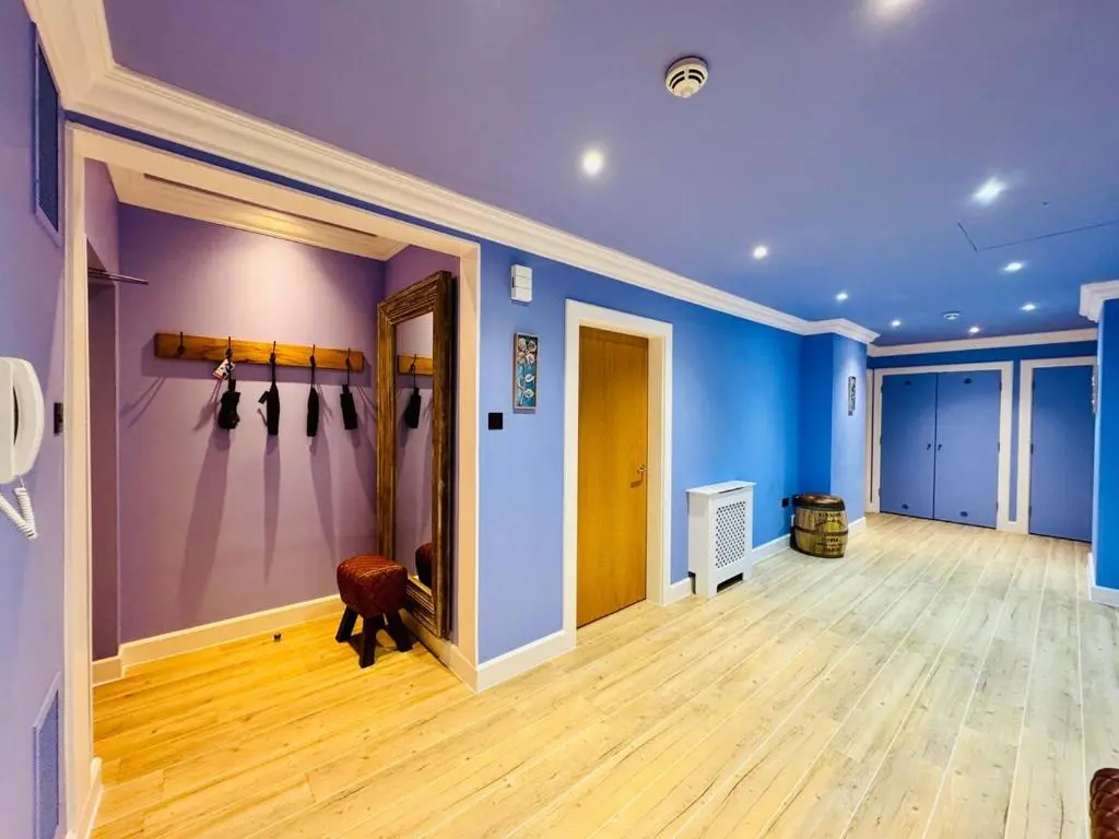 a room with blue walls and wooden floors and a hallway at Entirely New Monastery Renovation on Loch Ness in Fort Augustus