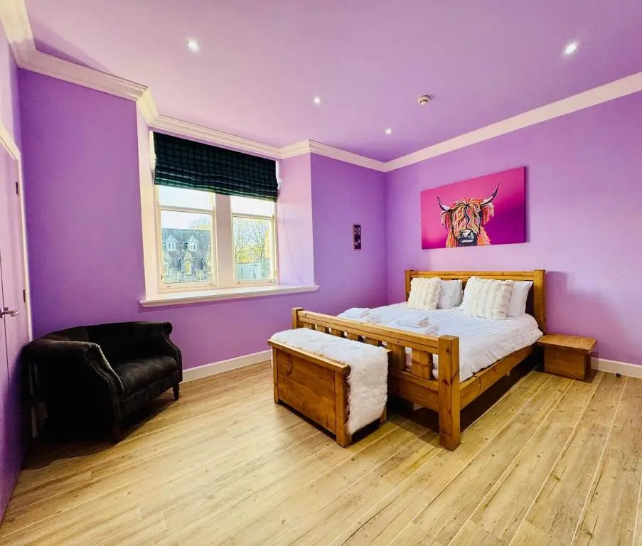 a bedroom with purple walls and a bed and a chair at Entirely New Monastery Renovation on Loch Ness in Fort Augustus