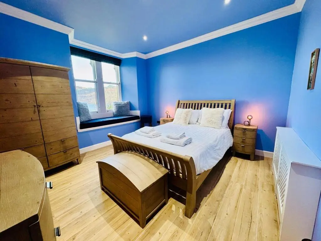 a bedroom with blue walls and a large bed at Entirely New Monastery Renovation on Loch Ness in Fort Augustus