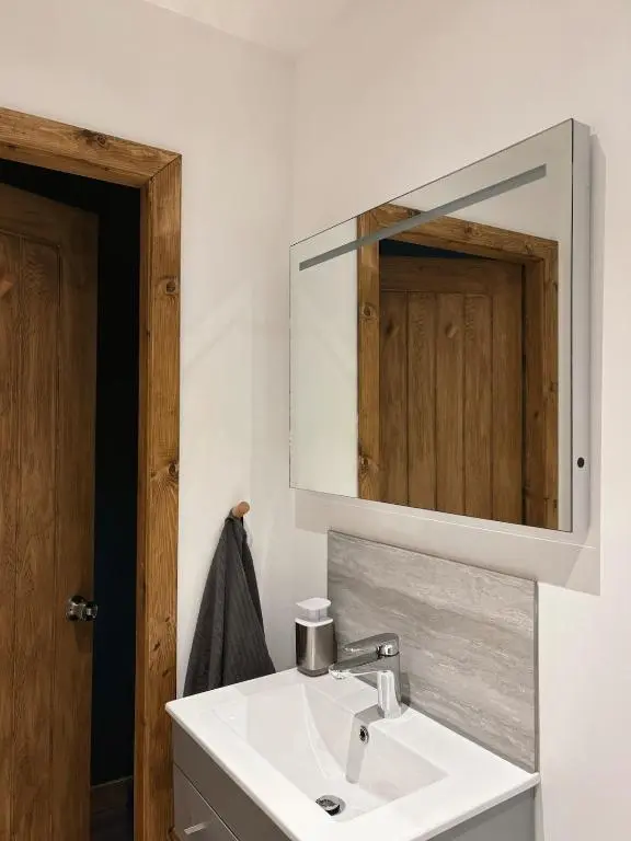 a bathroom with a white sink and a mirror at Bespoke Wood Cabin - Loch Ness in Inverfarigaig