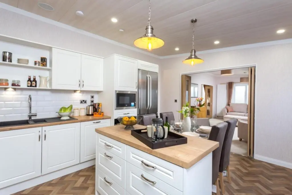 a kitchen with white cabinets and a dining room at Lyndale Lodge