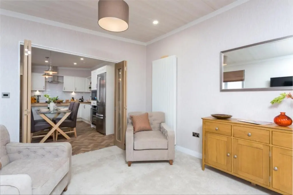 a living room with a couch and a chair and a kitchen at Lyndale Lodge