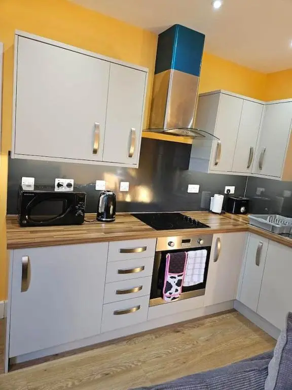 a kitchen with white cabinets and a stove top oven at City center apartment in Inverness
