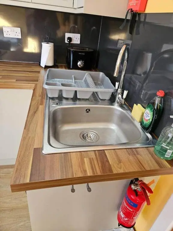 a kitchen sink with dishes in it on a counter at City center apartment in Inverness