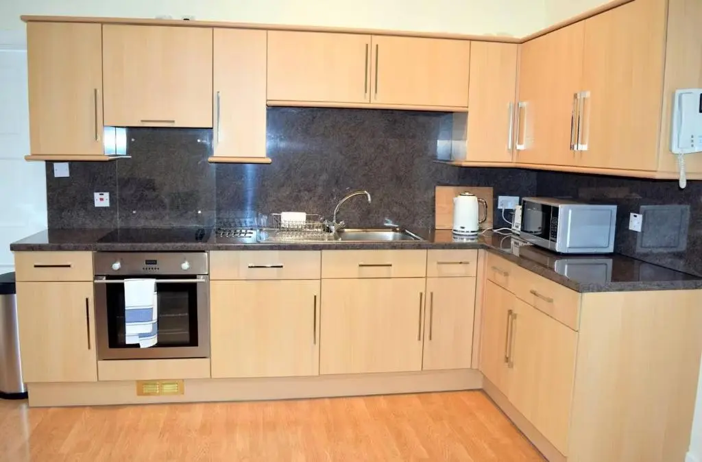 a kitchen with wooden cabinets and a sink and a microwave at Bankside - 1 En-Suite in Central - Free Parking in Wick