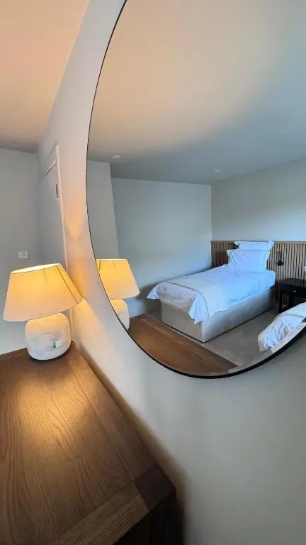 a bedroom with two beds and a circular mirror at No 67 West Road in Fraserburgh