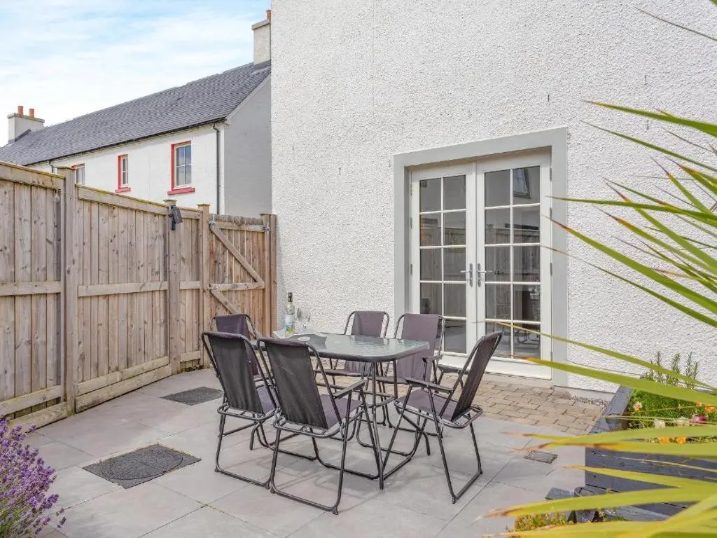 a patio with a table and chairs and a fence at One The Loan in Inverness
