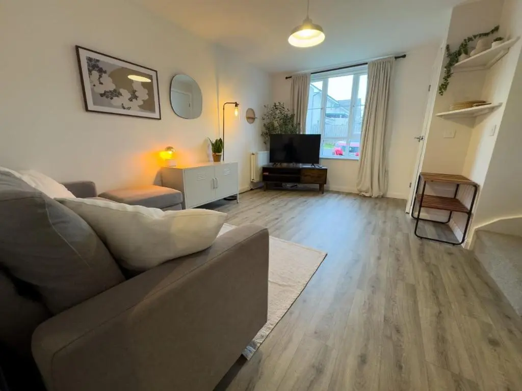 a living room with a couch and a television at Skibo Place House in Inshes