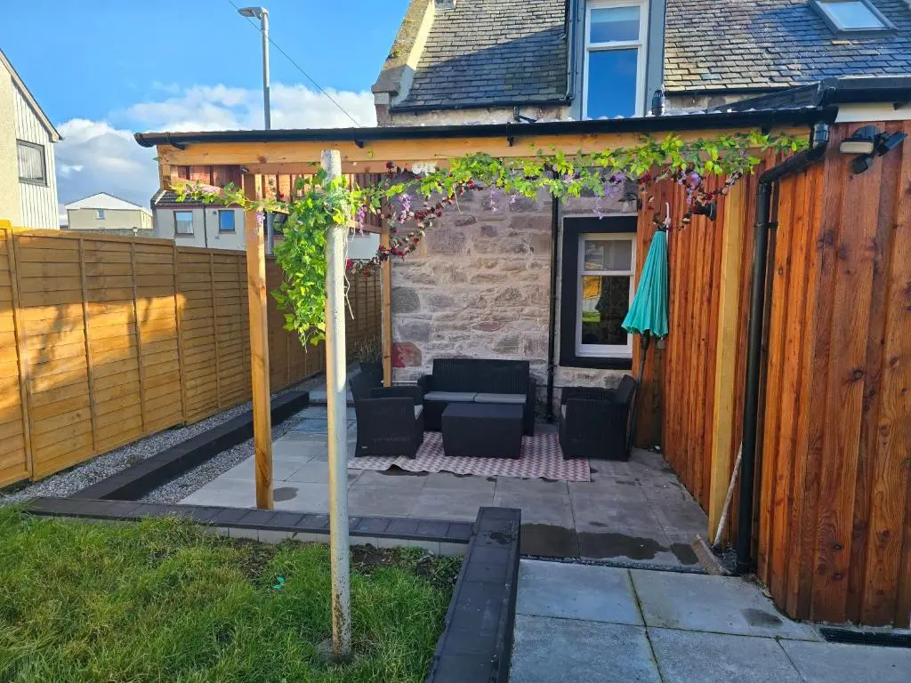 a patio with a table and chairs and a fence at Nanny bambi's three bedroom's in Inverness