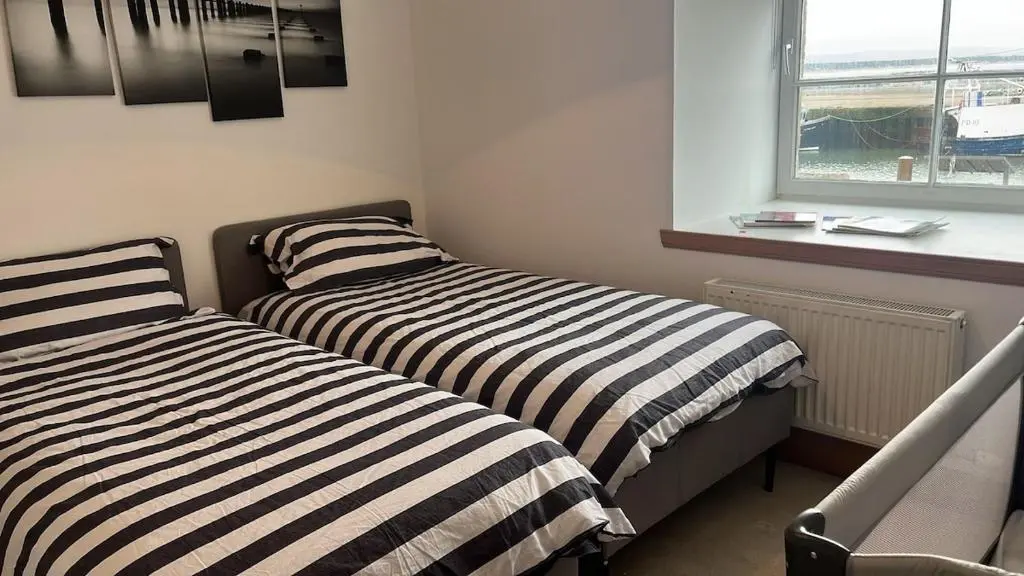 two beds in a small room with a window at Harbour Haven in Burghead