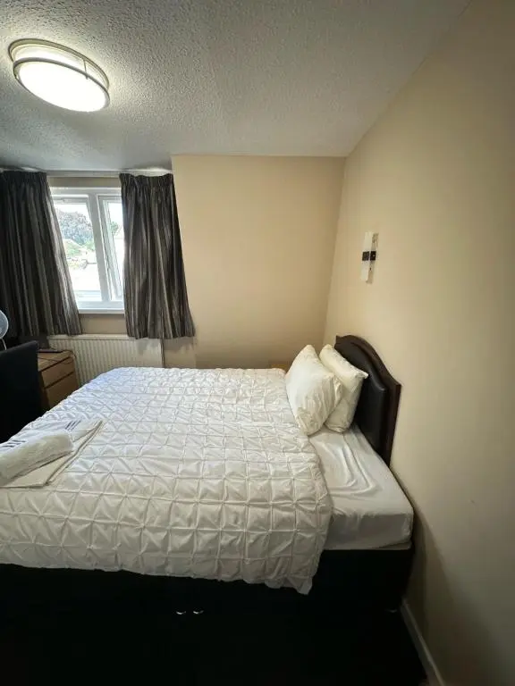 a bedroom with a bed with a white comforter and a window at Burnett Arms Hotel in Banchory
