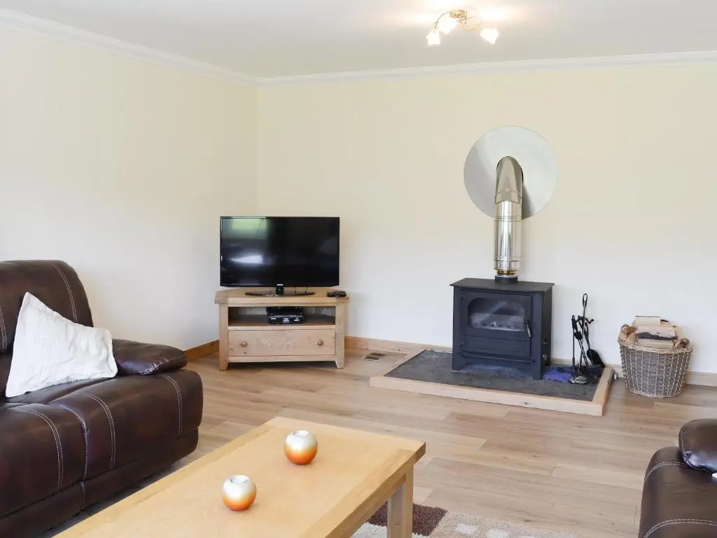 a living room with a couch and a stove at March Cottage in Glenrossal