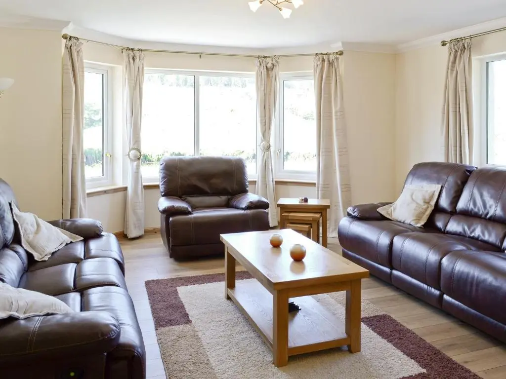 a living room with leather couches and a coffee table at March Cottage in Glenrossal