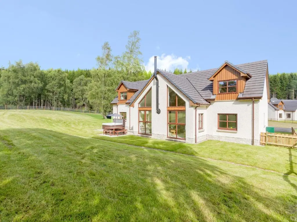 a house on a grassy hill with a yard at Birch Corner in Aviemore