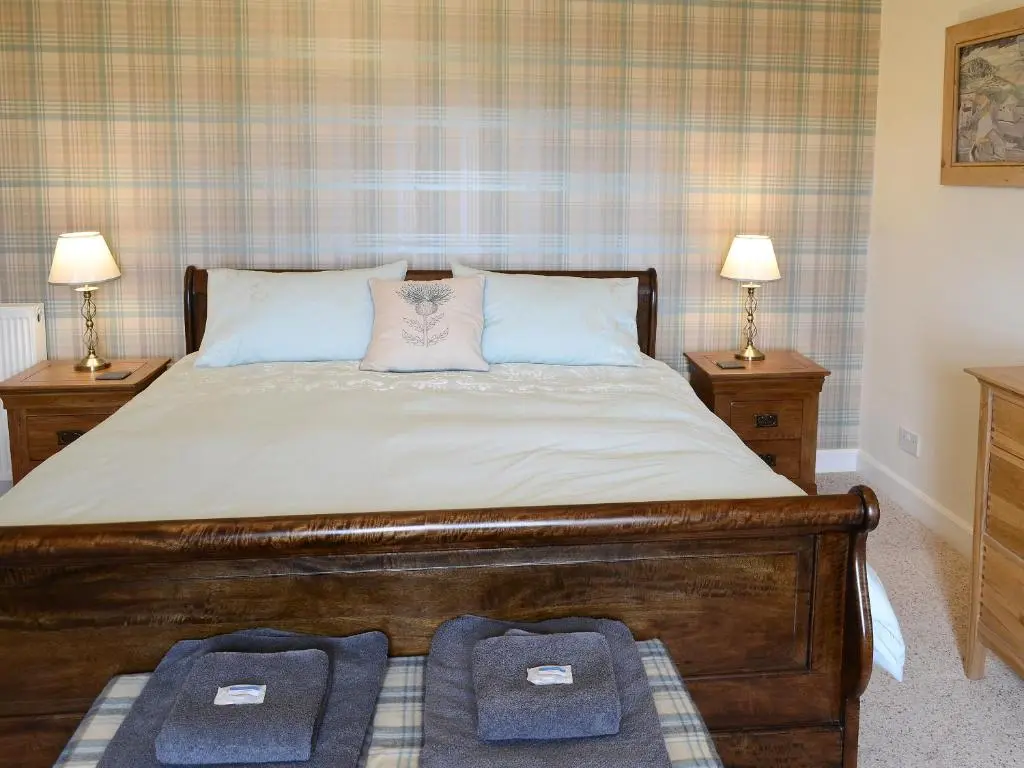 a bedroom with a large bed with two night stands at Drummuie House in Golspie