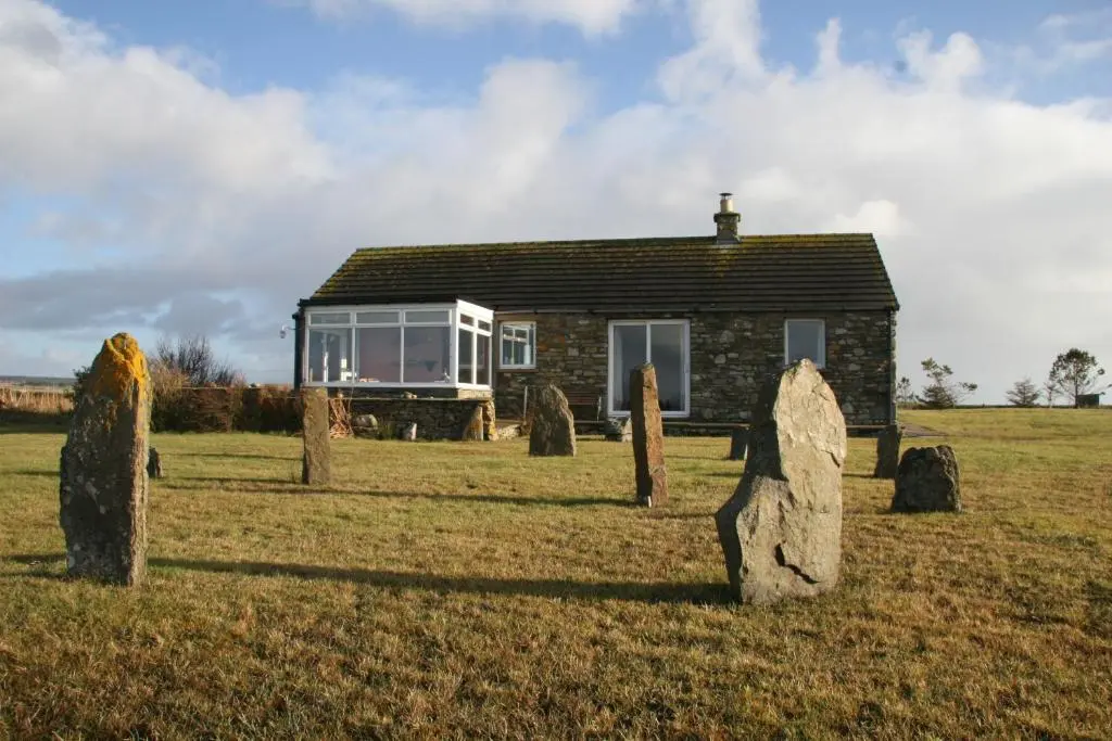 a small stone house in a field with rocks in front of it at Taigh An Clachair in Lybster