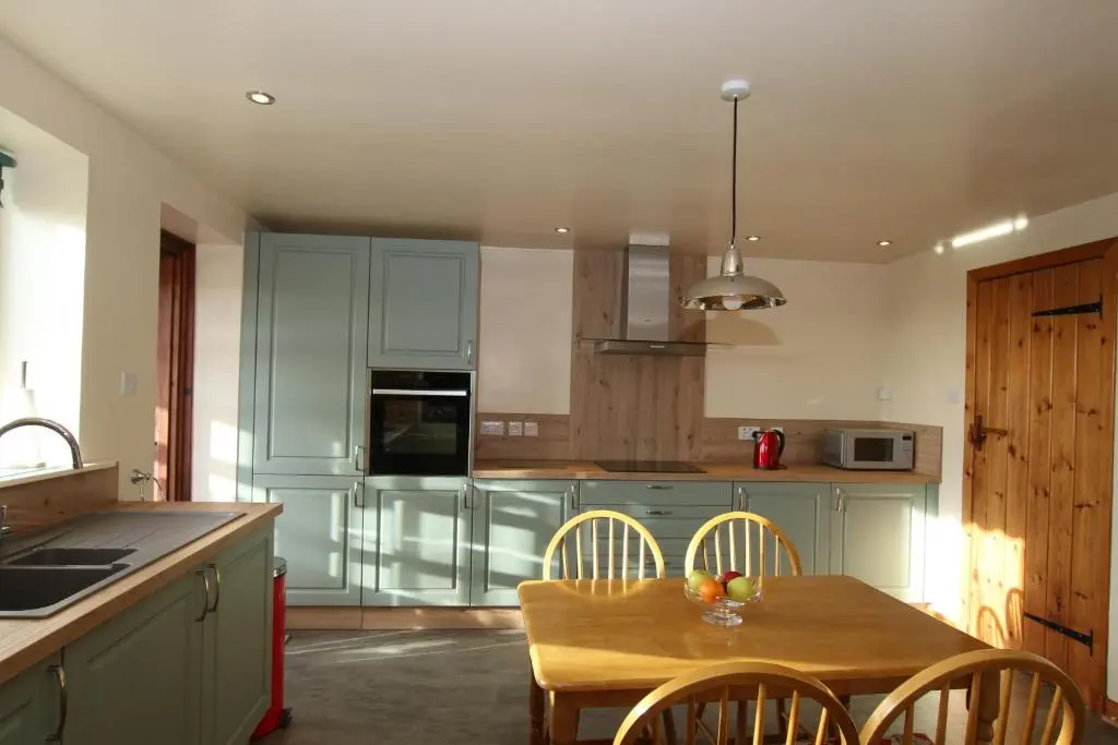 a kitchen with a wooden table and chairs in it at Taigh An Clachair in Lybster