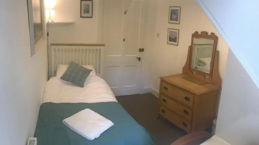 a small bedroom with a bed and a mirror at Carrick House in Kingussie
