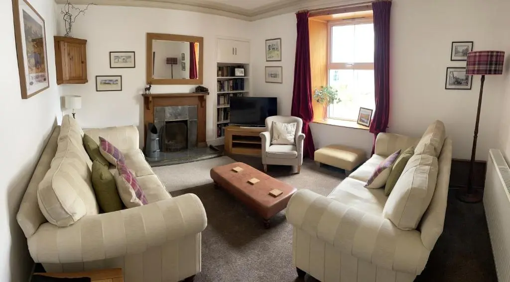 a living room with two couches and a fireplace at Carrick House in Kingussie