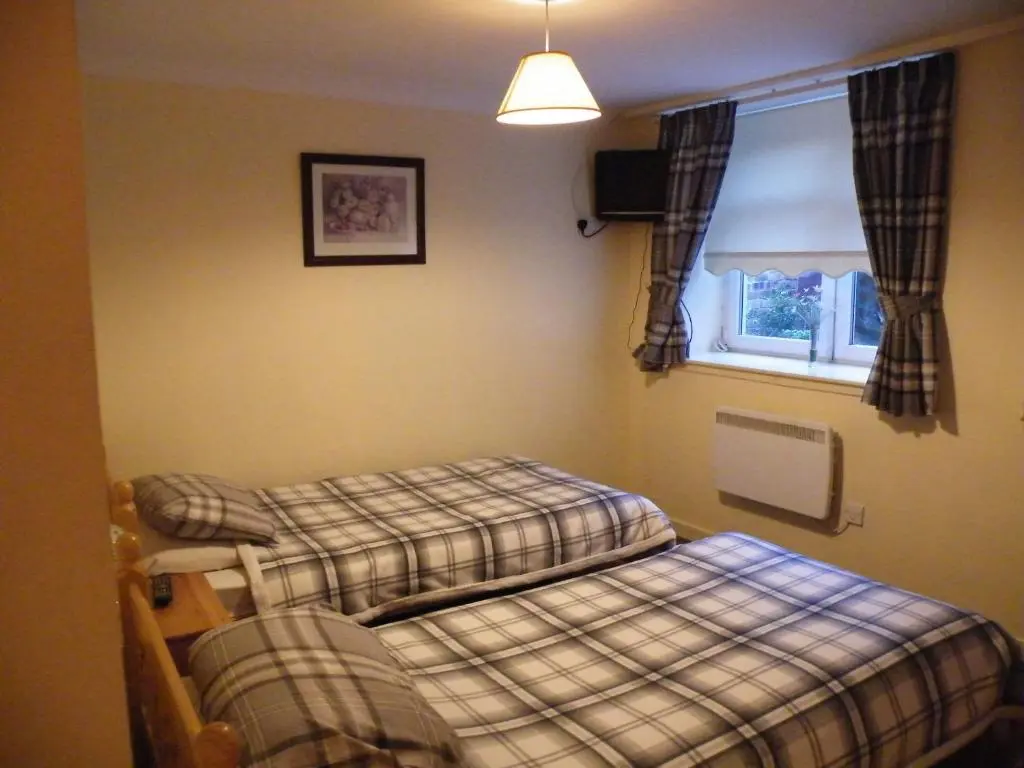 a room with two twin beds and a window at Coasters Holiday Flats in Macduff