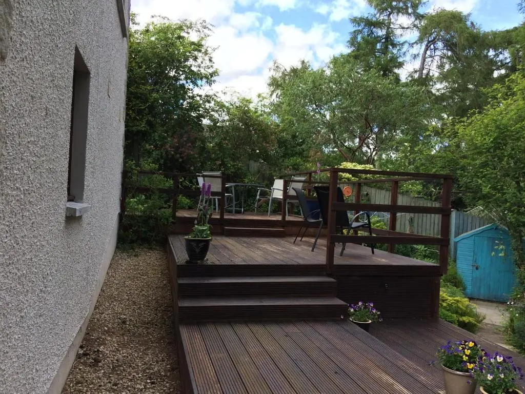 a wooden deck with stairs next to a house at Dullatur in Newtonmore
