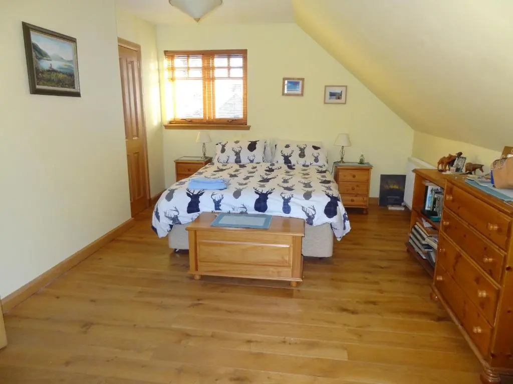 a bedroom with two beds and a wooden floor at Dullatur in Newtonmore