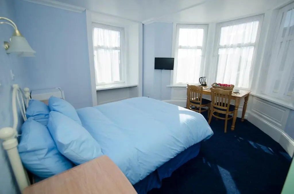 a bedroom with a bed and a table and windows at Elgin City Centre Torr House hotel in Elgin