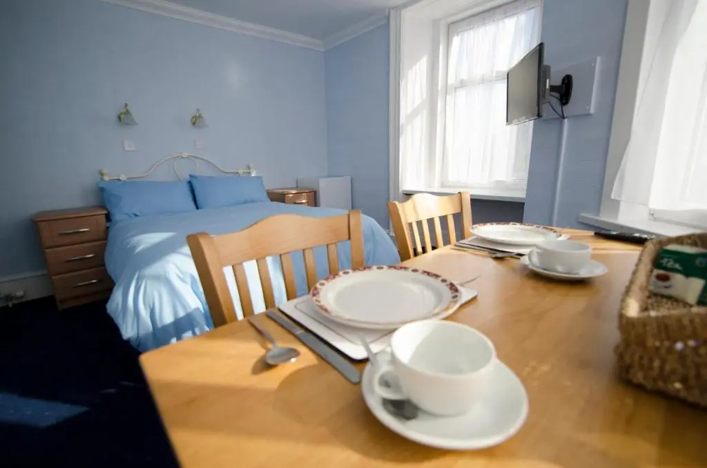 a dining room with a table and a bed at Elgin City Centre Torr House hotel in Elgin