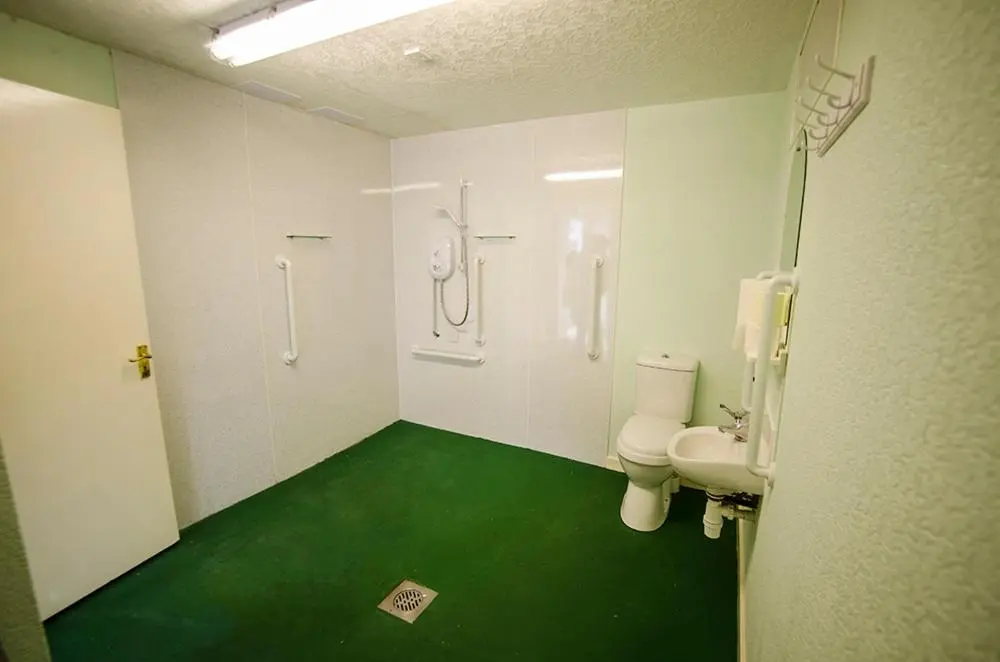 a bathroom with a toilet and a green floor at Elgin City Centre Torr House hotel in Elgin