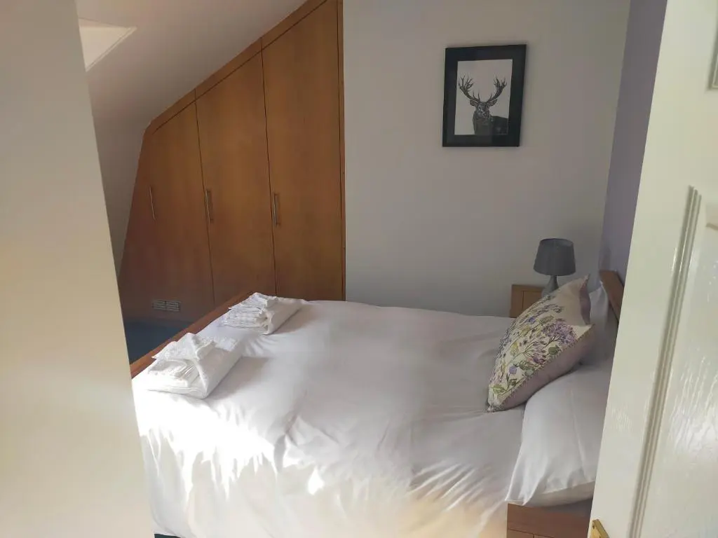 a bedroom with a white bed with a wooden headboard at The Loft, Inverness in Inverness