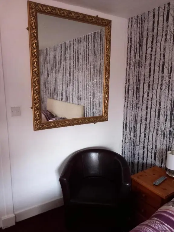 a mirror on a wall next to a black chair at Aberdeen Arms Hotel Tarland in Tarland