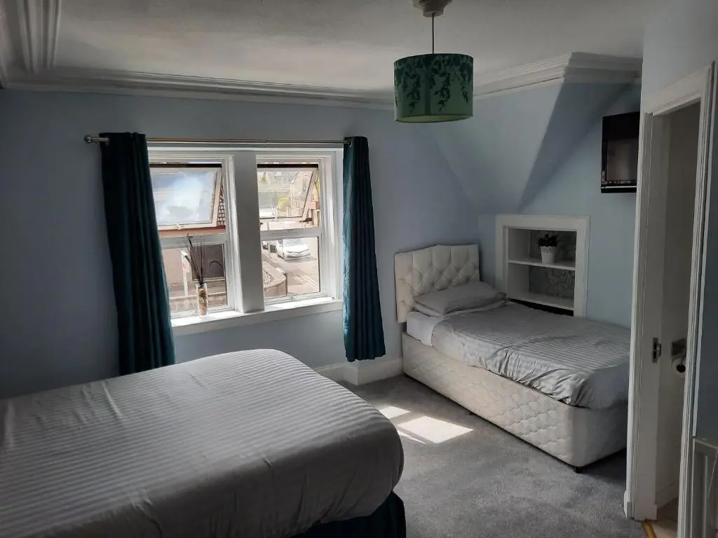 a bedroom with two beds and a window at Jacobite Rose in Inverness