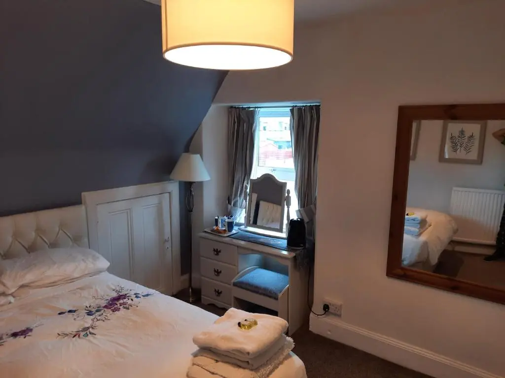 a bedroom with a bed and a dresser and a mirror at Jacobite Rose in Inverness
