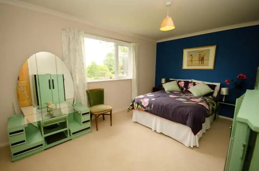 a bedroom with a bed and a mirror and a chair at Home Comforts in Peaceful 2 Acres in Inverness