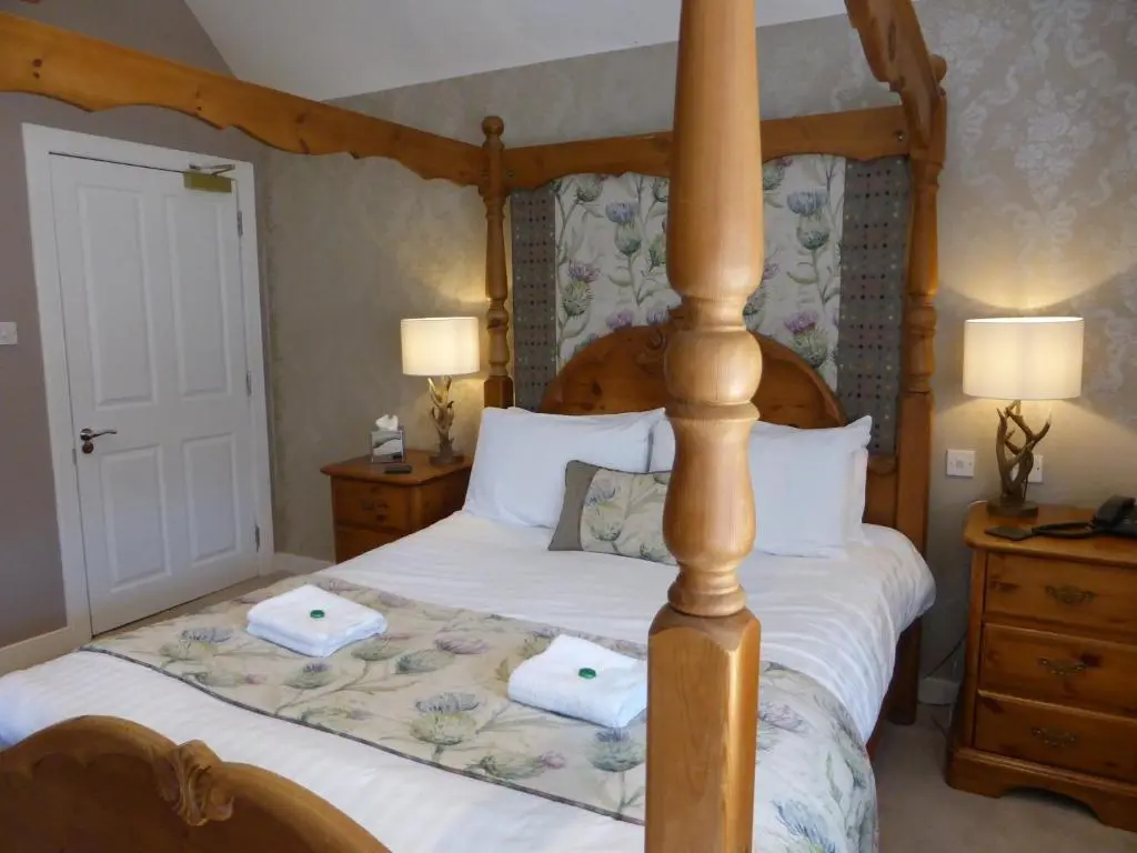 a bedroom with a four poster bed with two towels at Glen Clova Hotel & Luxury Lodges in Millton of Clova
