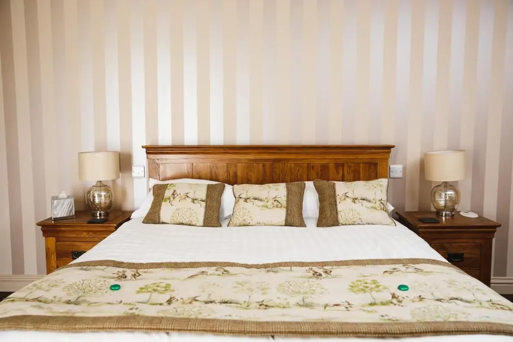 a bedroom with a bed with two lamps on tables at Glen Clova Hotel & Luxury Lodges in Millton of Clova