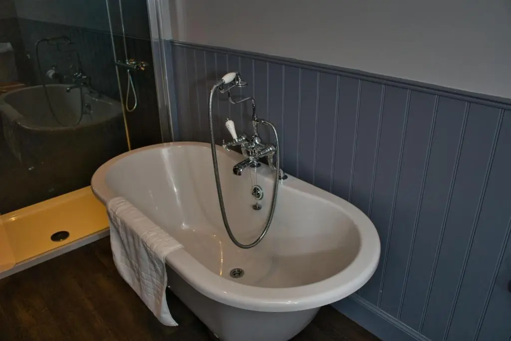 a bath tub in a bathroom with a shower at Glen Clova Hotel & Luxury Lodges in Millton of Clova