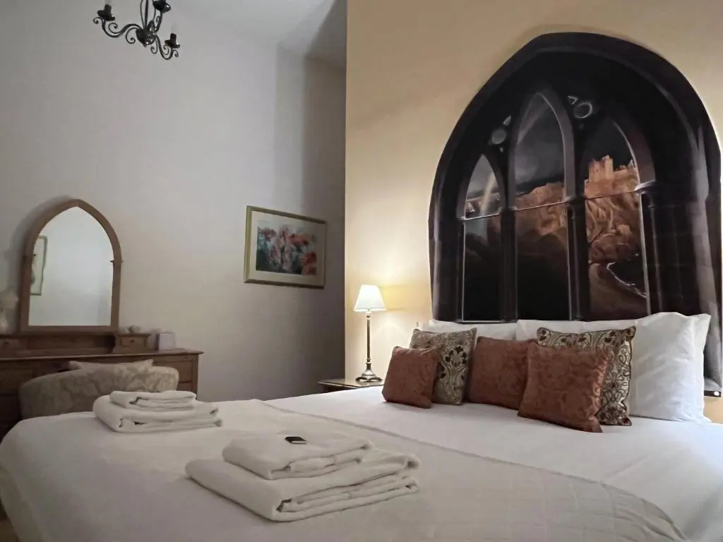 a bedroom with a large bed with towels on it at The Classrooms, Loch Ness Abbey - 142m2 Lifestyle & Heritage apartment - Pool & Spa - The Highland Club - Resort on lake shores in Fort Augustus