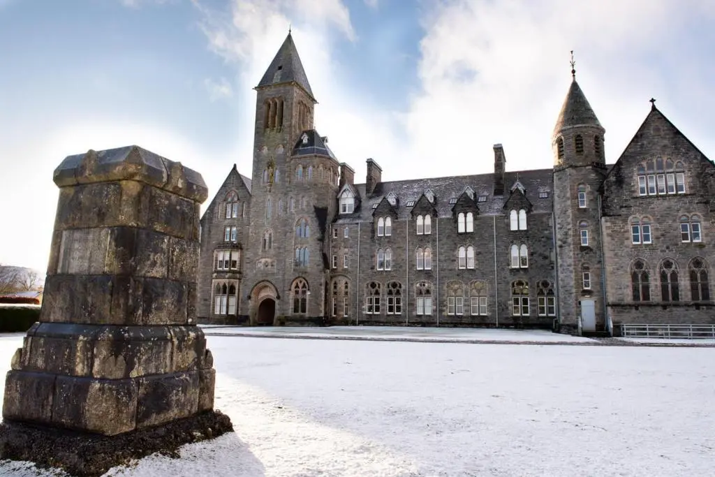 an old building with snow in front of it at Boys Dormitory in Fort Augustus