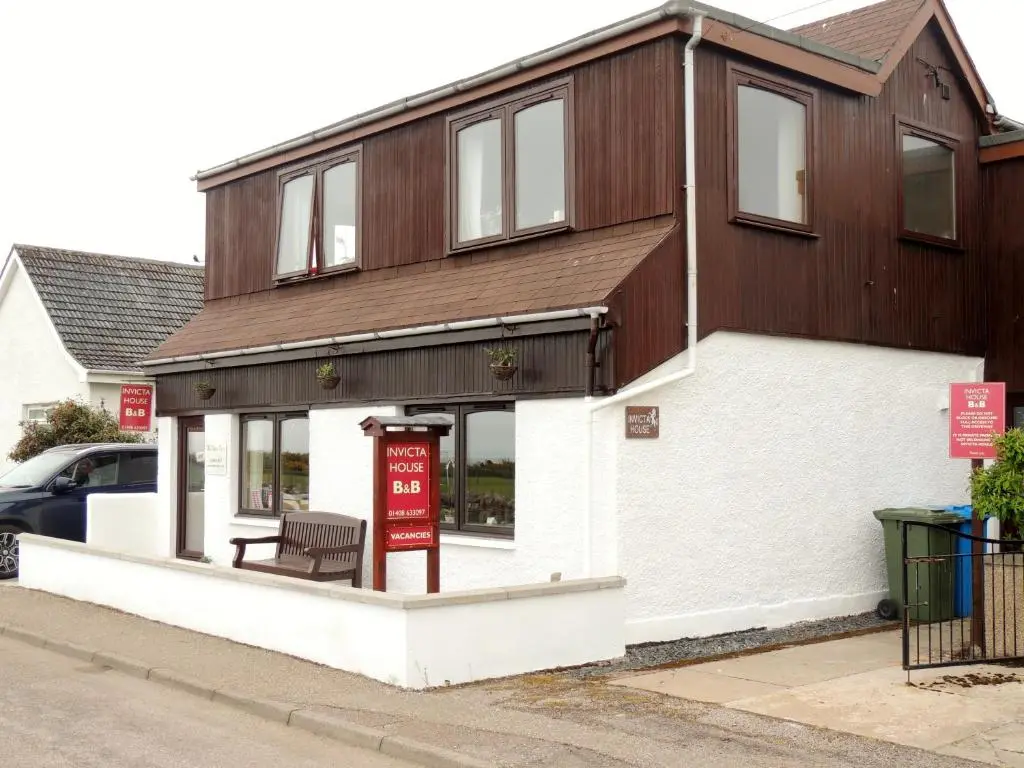 a building with a red sign in front of it at Invicta House B&B in Golspie