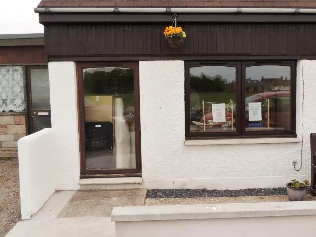 a building with four windows with a potted plant on it at Invicta House B&B in Golspie