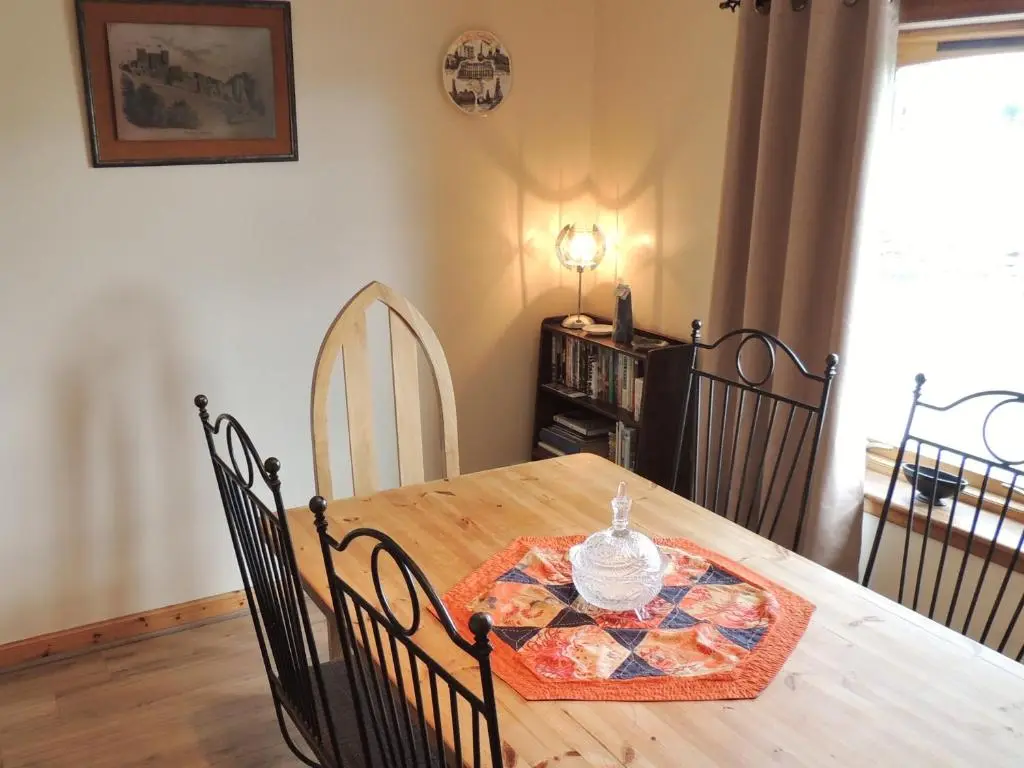 a dining room with a wooden table and chairs at Invicta House B&B in Golspie