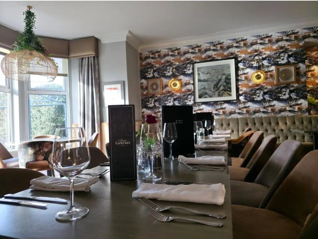 a restaurant with a long table with wine glasses at Beaufort Hotel in Inverness