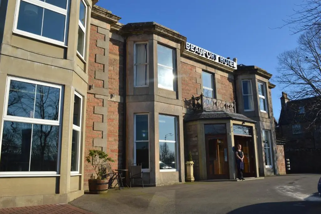 a woman standing in the doorway of a brick building at Beaufort Hotel in Inverness