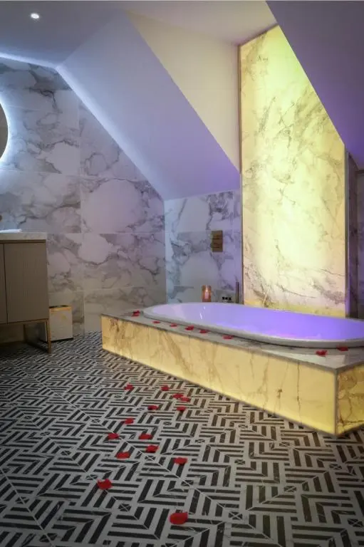 a bathroom with a tub and a marble wall at Beaufort Hotel in Inverness