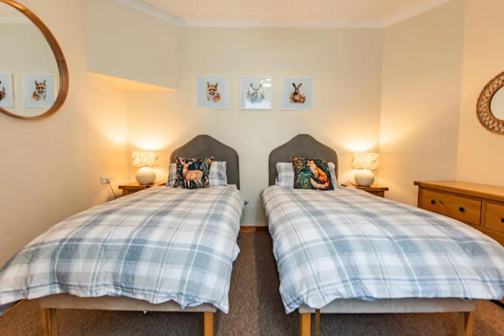 two twin beds in a room with a mirror at Elgin Self Catering Holiday Cottage in Elgin