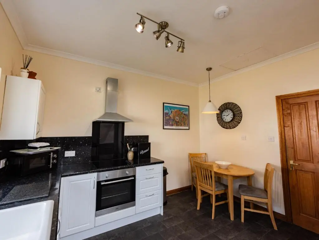 a kitchen with a table and a stove top oven at Elgin Self Catering Holiday Cottage in Elgin